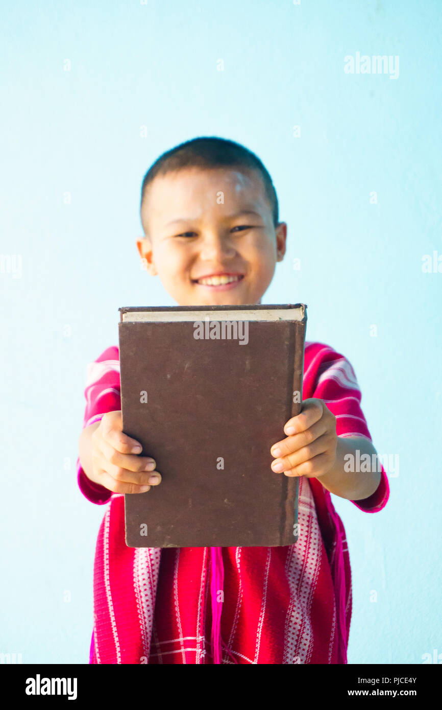 Little boy Holding in einem großen Buch auf einem hellblauen Hintergrund. Stockfoto