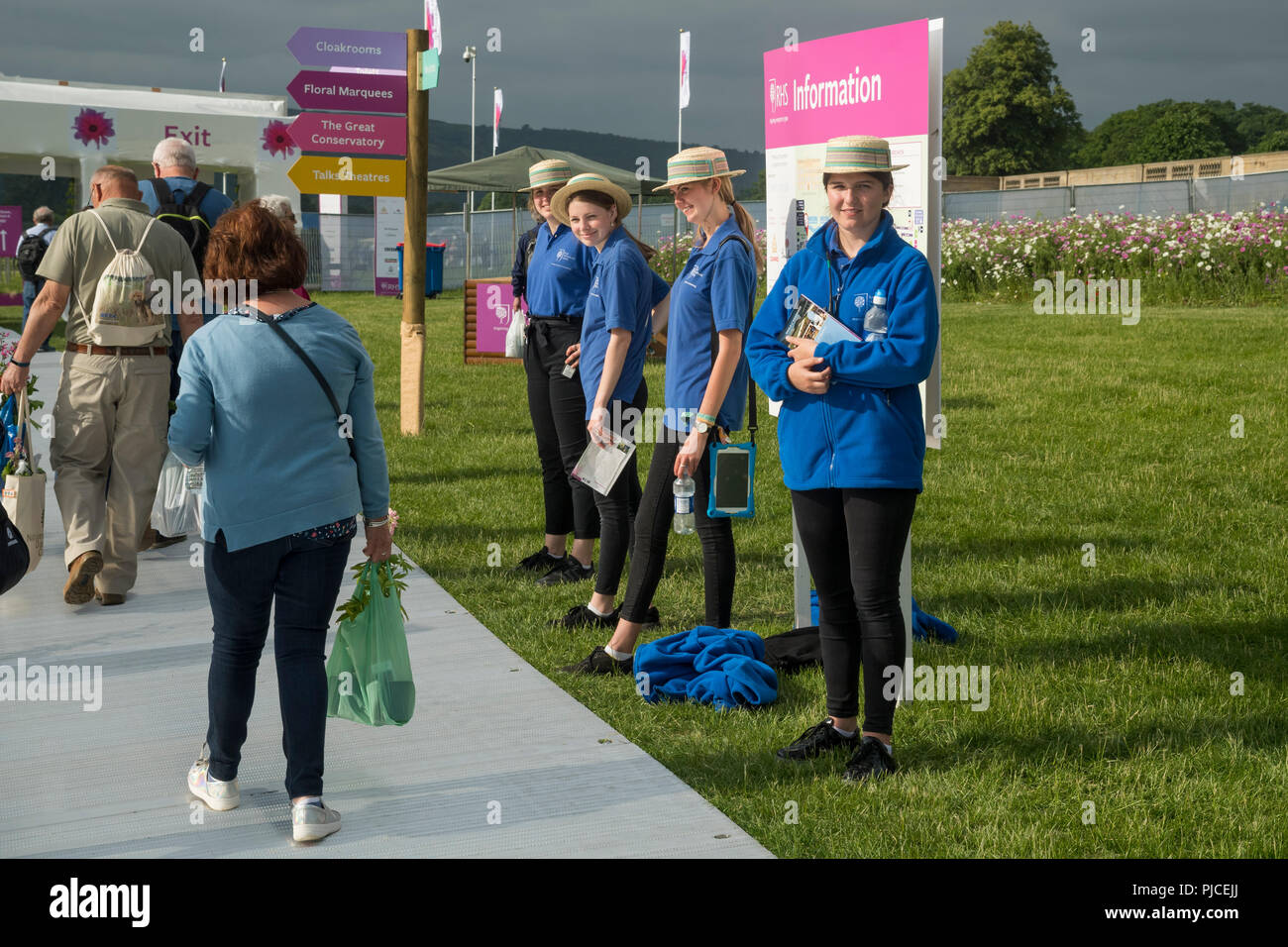 4 Junge weibliche Führer oder welcomers stand by Information Board&Smile herzlich als Besucher von RHS Chatsworth Flower Show, Derbyshire, England, UK zu Fuß Stockfoto