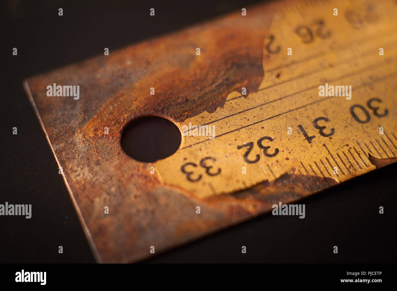 Altes rostiges Metall Lineal mit numerierten Etiketts Risse auf schwarzem Hintergrund Oberfläche mit kostenlose Kopie Raum Stockfoto