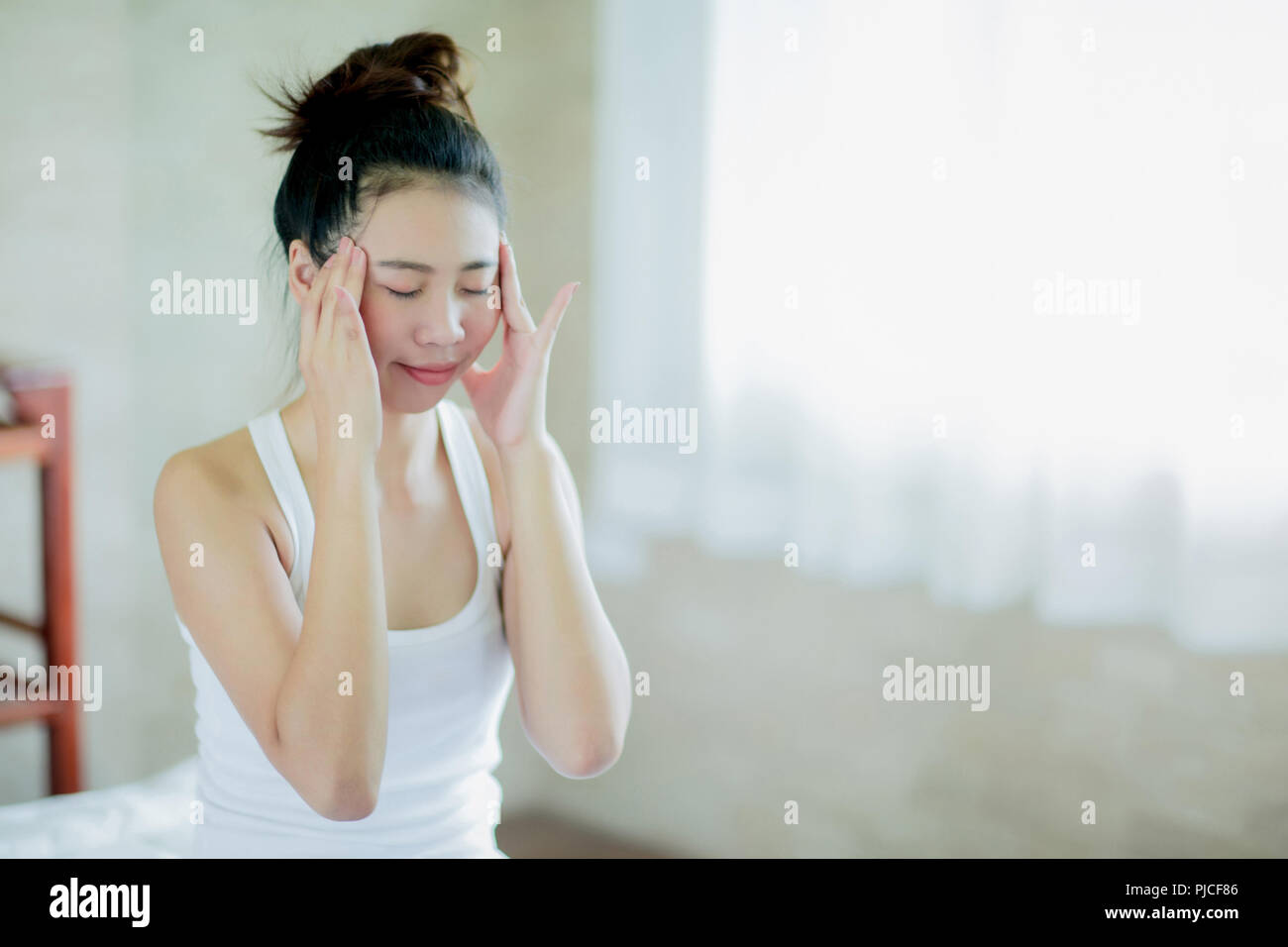 Asiatische Frau Massagen ihr Tempel für lindern Kopfschmerzen zu Hause Stockfoto