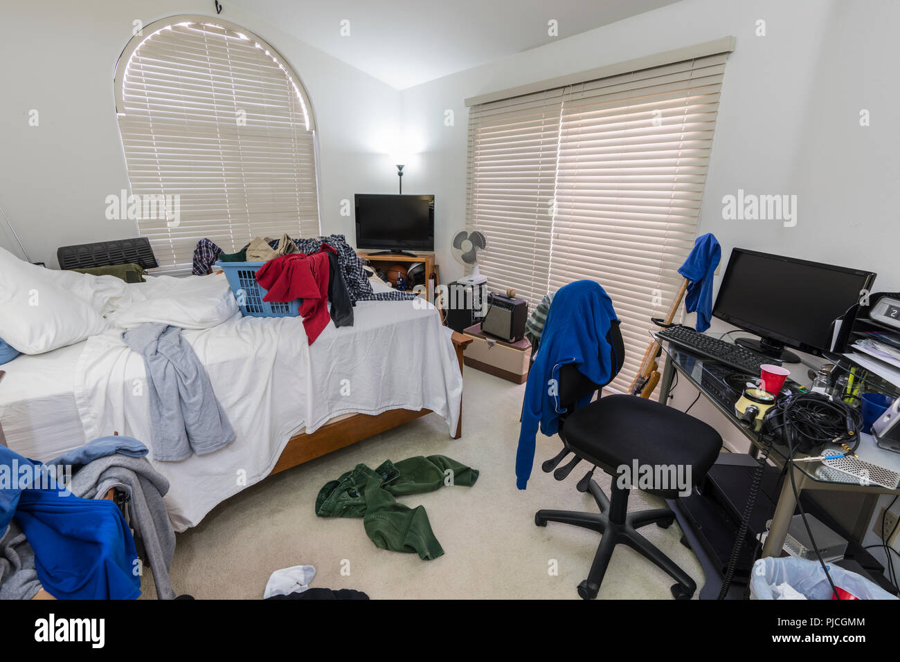 Überladen, unordentlichen Jungen im Teenageralter Schlafzimmer mit Stapel von Kleidung, Musik und Sportgeräte. Stockfoto