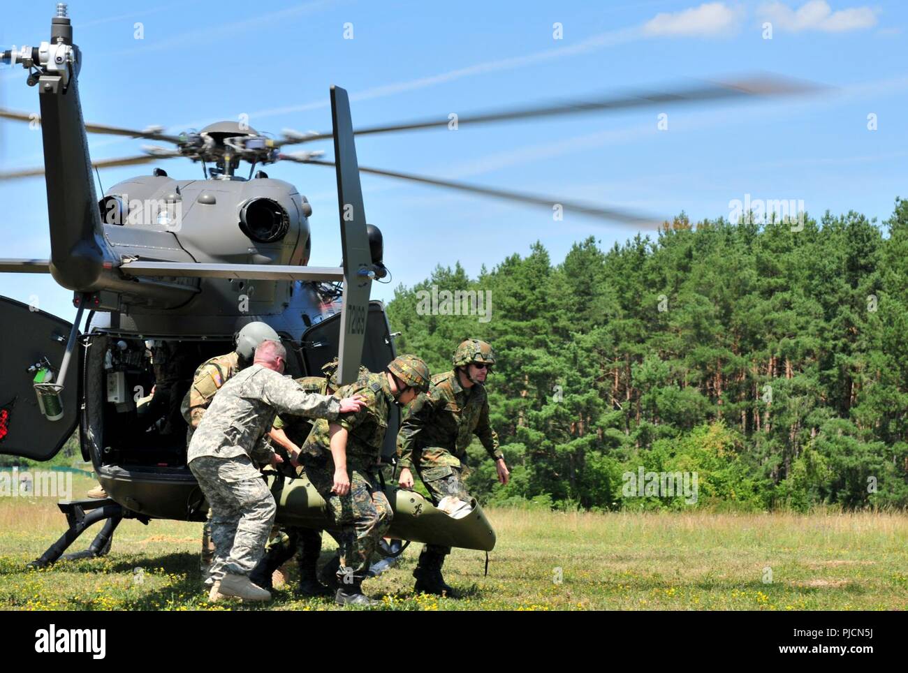 Us-Armee Kapitän Morris Duffy (links vorne), einen Flug Chirurg auf das erste Bataillon zugeordnet, 112 Aviation Regiment, Oklahoma Army National Guard, hilft bei der Deutschen Bundeswehr Reservisten mit medizinische Luft Evakuierungsübung in Hohenfels training Bereich der Gemeinsamen Multinationalen die Bereitschaft, Hohenfels, Deutschland, Juli 19, 2018 Zug. Nebraska und Kansas Army National Guard Soldaten beteiligen sich an multinationalen Interoperabilität Ausbildung, mit der die Beziehung zwischen den USA und dem Gastgeberland verbessert. Stockfoto