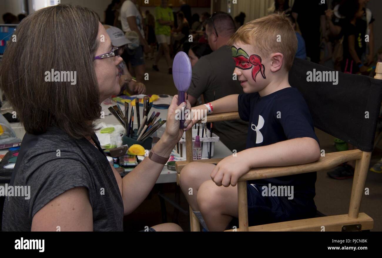 Mac, 6, sieht in einem Spiegel nach seinem Gesicht Malerei an der jährlichen Summer Slam Base Picknick an der Schriever Air Force Base, Colorado, 20. Juli 2018 abgeschlossen ist. 50. Kraft Support Squadron Gastgeber der Veranstaltung mit Unterstützung von mehr als 70 Freiwilligen. Stockfoto