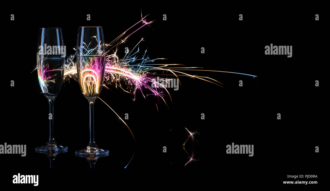 Zwei hohe Gläser Champagner vor dem Hintergrund der bengalischen Lichtern. Schwarzen Hintergrund. Das Konzept der Feier der Hochzeit und der neue Ja Stockfoto