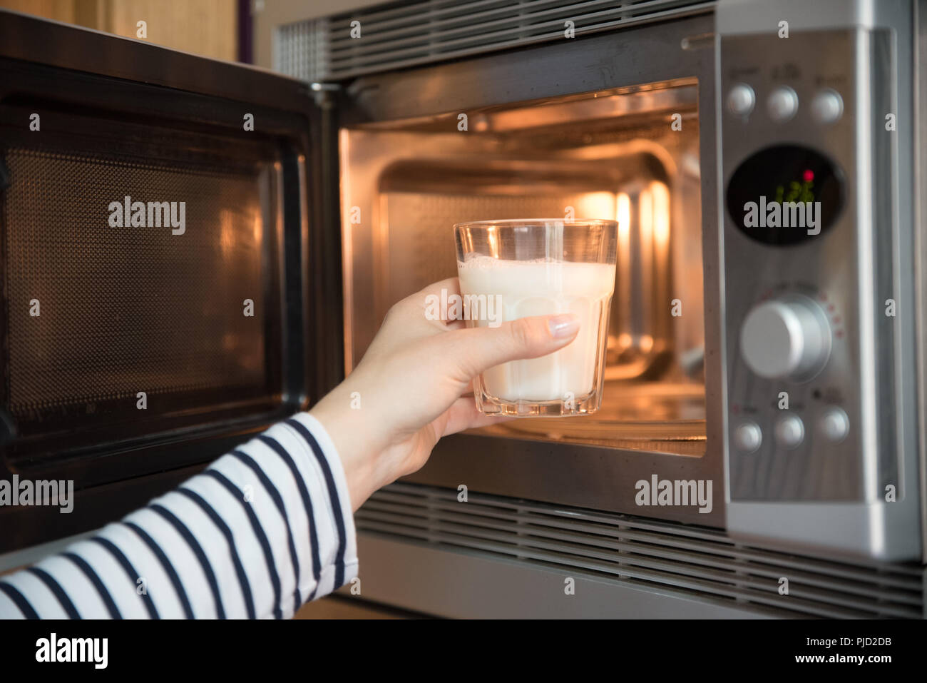 Frau Erwärmung ein Glas Milch in der Mikrowelle Stockfotografie - Alamy