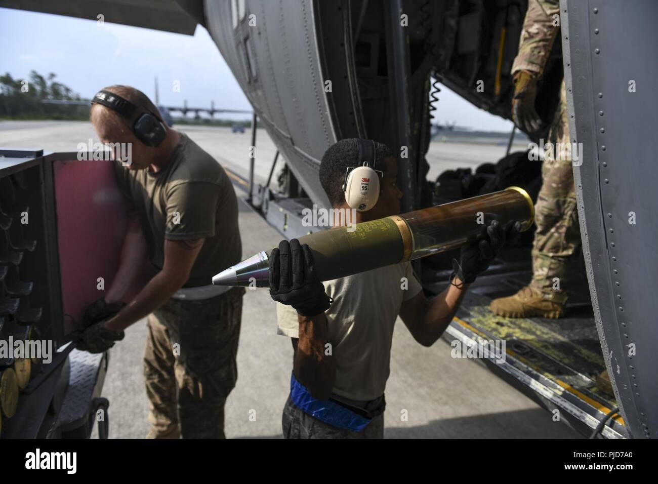 Eine Munitions systeme Techniker mit der 1 Special Operations Maintenance Squadron Transfers 105 mm hoch explosiven Runden aus dem Lager zu US Air Force Tech. Sgt. Brett Laswell, eine spezielle Missionen Aviator und Bewerter mit der 4 Special Operations Squadron, Juli 18, 2018, at Hurlburt Field, Florida. Das bodenpersonal mit der 4. SOS führte eine Live-Fire Training Mission für die Bekämpfung von Fähigkeiten zu schärfen und die Bereitschaft zu gewährleisten. Stockfoto