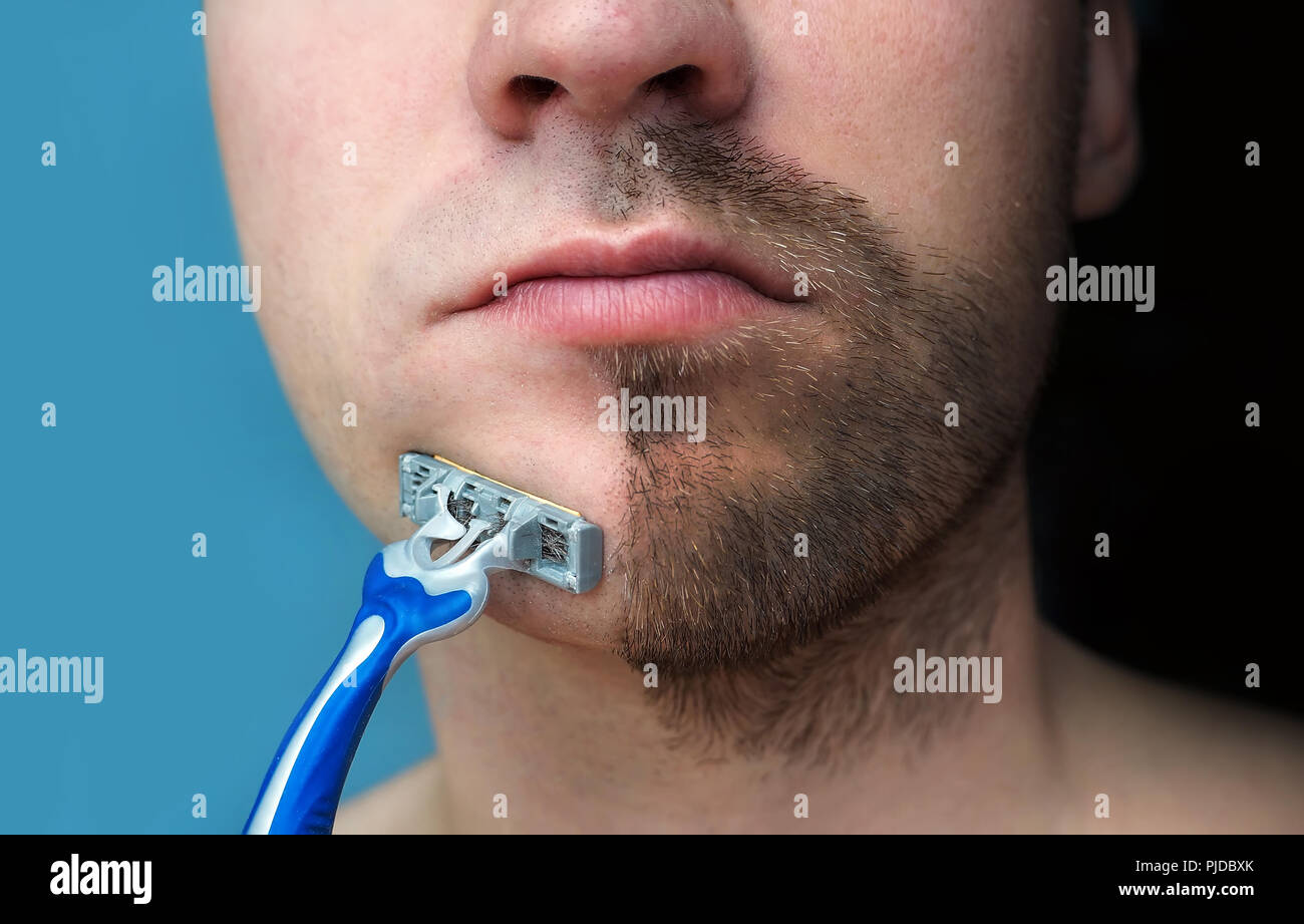 Ein Mann rasiert sein Gesicht ohne Creme oder Schaum, Schmerzen und Leiden.  Die Hälfte Gesicht rasiert Halb überwachsen mit einer dicken Bart  Stockfotografie - Alamy