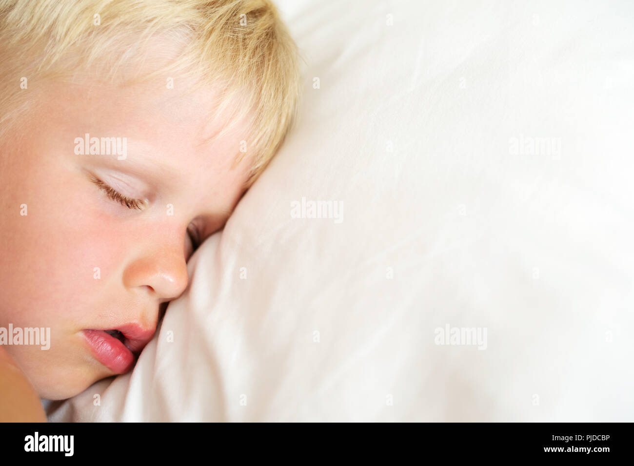 Blondy kleiner Junge Schlafen auf weißen Kissen. Sweet Dream Konzept. Ansicht von oben. Stockfoto