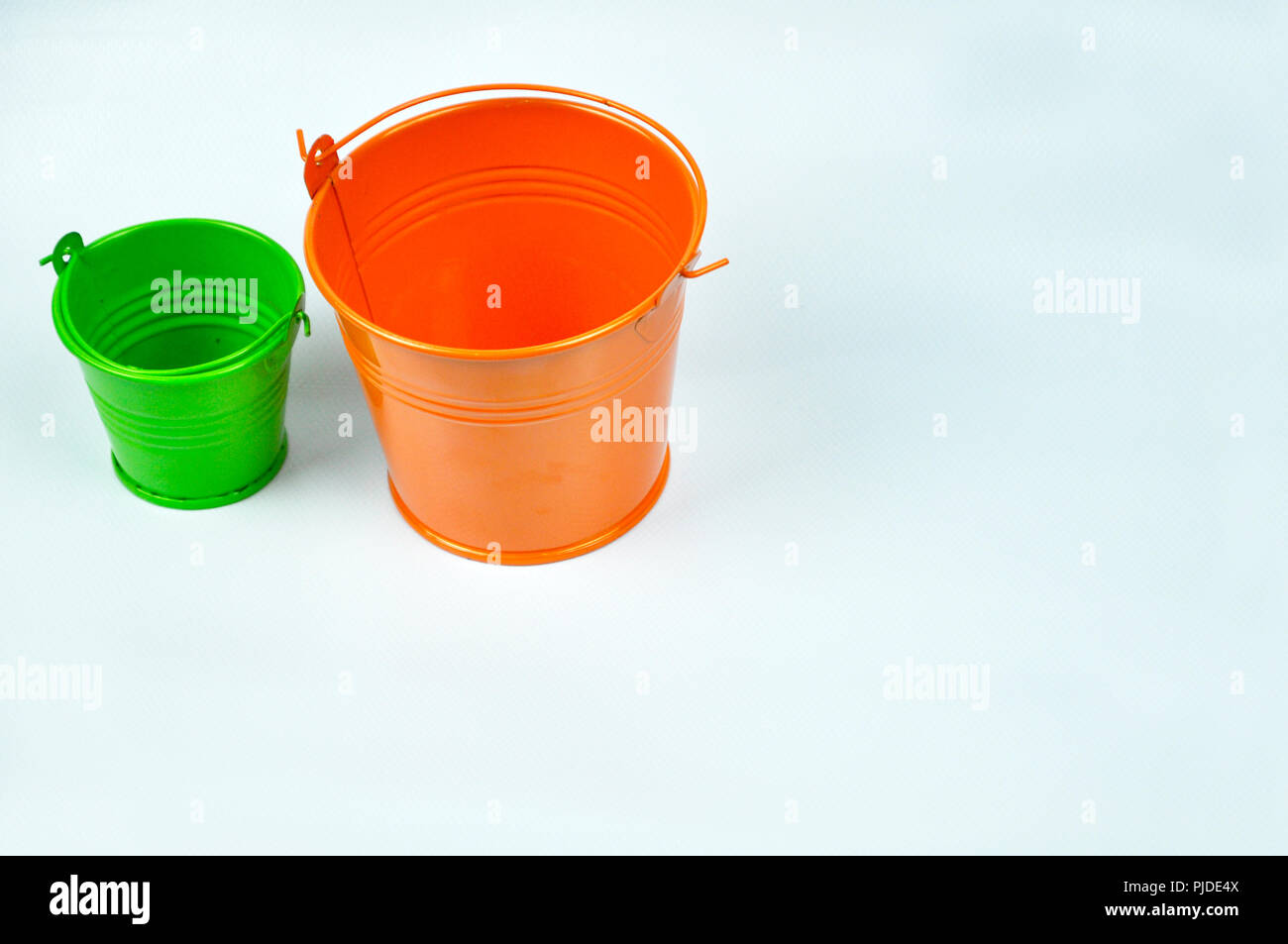 Kleine orange und grüne Eimer auf weißem Hintergrund. Stockfoto