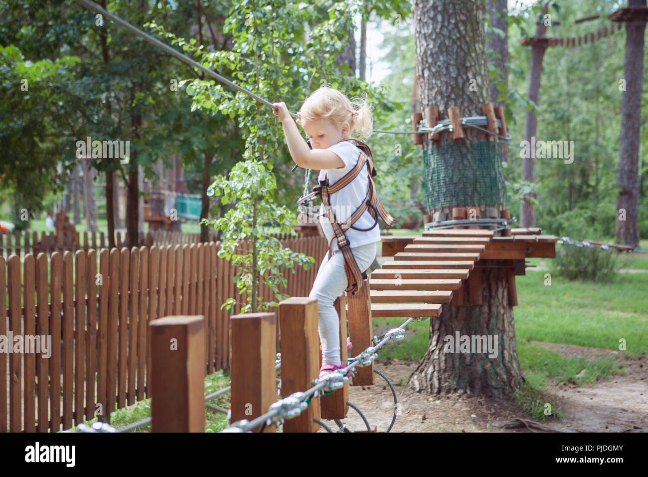 Kleines Mädchen in Gang übergibt ein Hindernis im Seilpark. Stockfoto