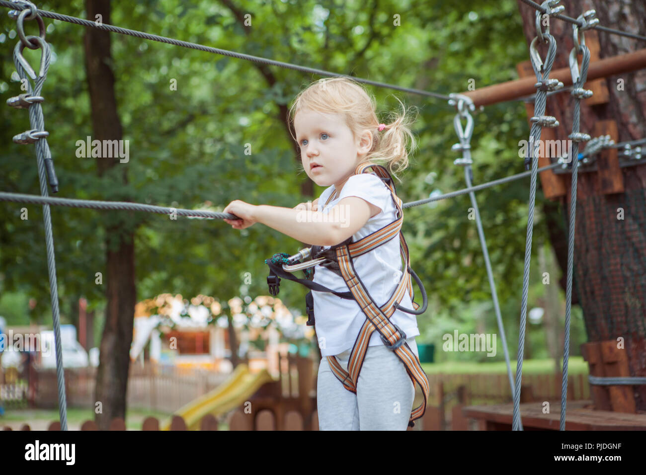 Porträt eines tapferen kleinen Mädchen im Seilpark. Sie gibt dem Hindernis. Stockfoto