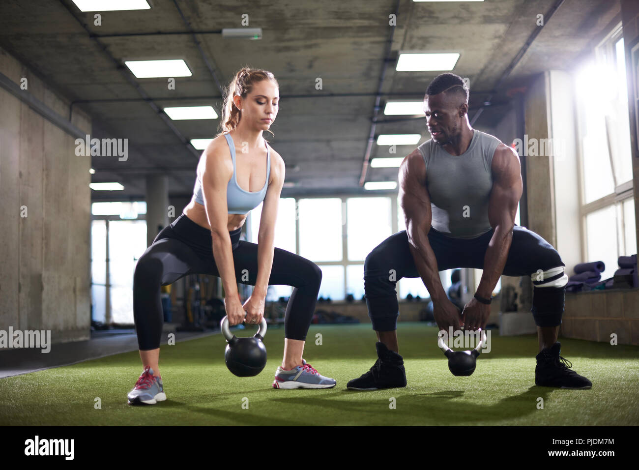 Trainer und weibliche client Übung mit den Kettlebells in der Turnhalle Stockfoto