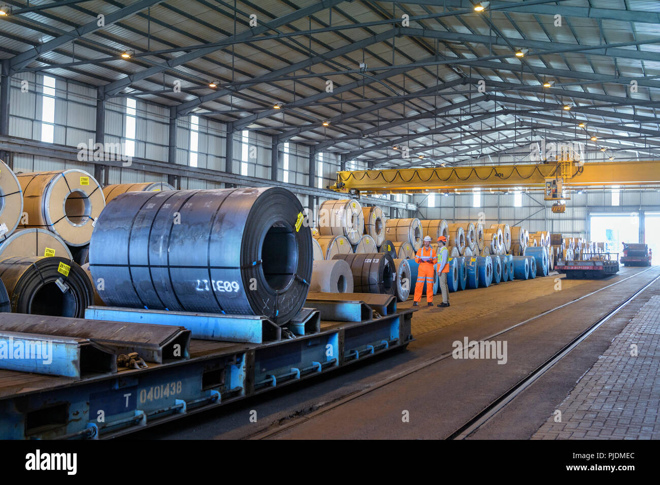 Arbeitnehmer mit Reihen von Stahlblech in der Lagerung im Hafen Stockfoto