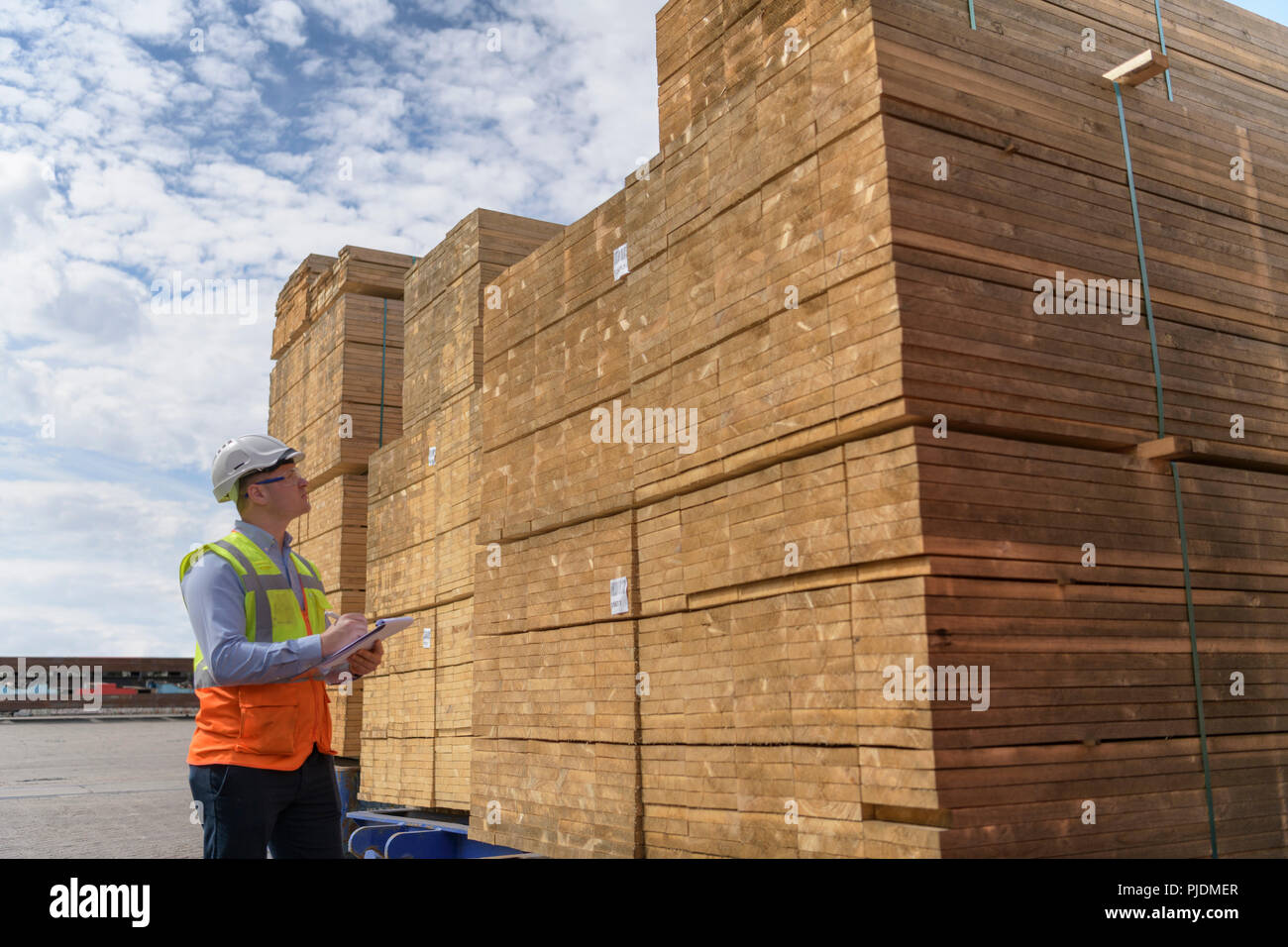 Arbeitnehmer mit Stapeln von Holz in der Lagerung im Hafen Stockfoto