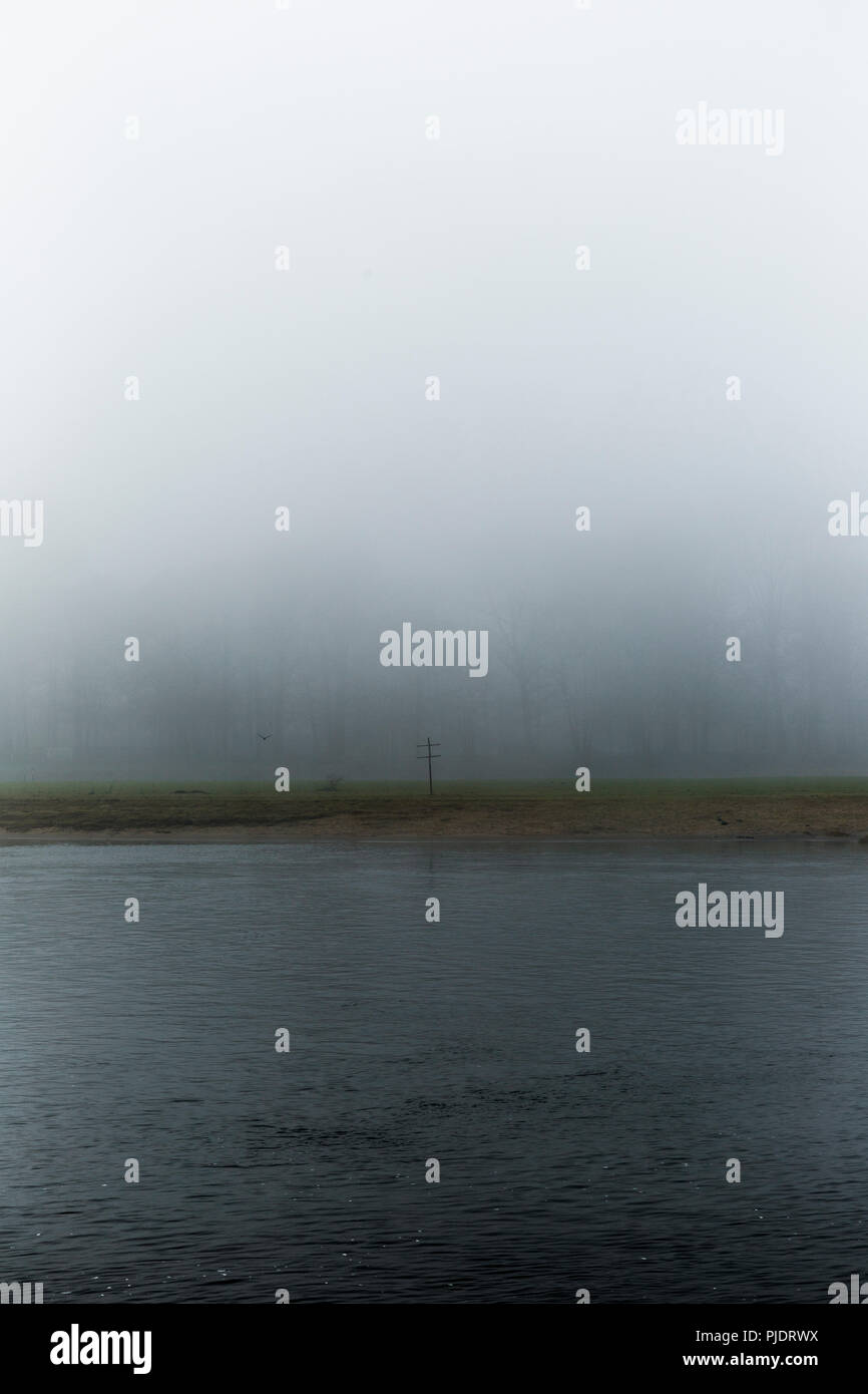 Dunkler Nebel Landschaft mit hölzernen Kreuz auf der anderen Seite. Stockfoto