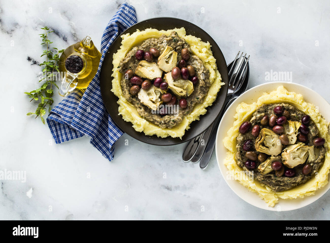 Zwei Platten mit Kartoffelpüree, Baba ganush, in Öl und Oliven auf den Tisch Artischocken. Gesunde vegane Küche Stockfoto