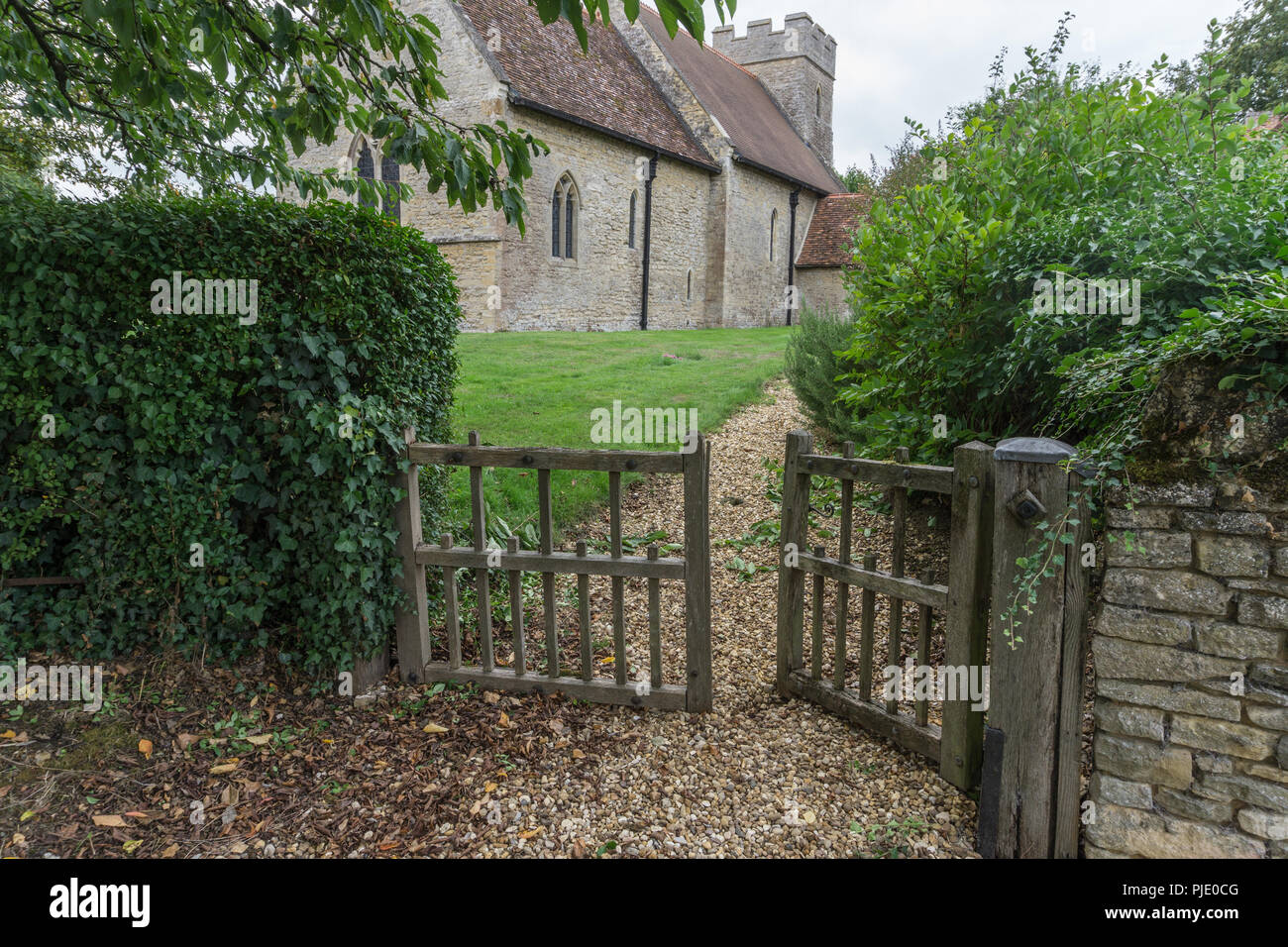 Alte hölzerne Tore und ein schotterweg Zur historischen Kirche St. Maria im Dorf Cold Brayfield, Bedfordshire, Großbritannien Stockfoto