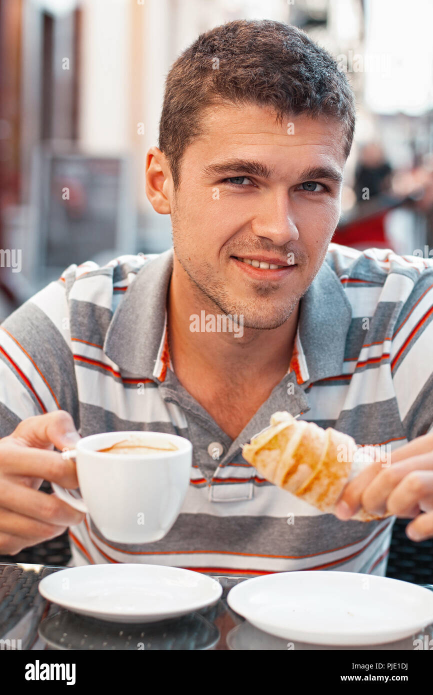 Junger Mann trinkt Kaffee mit Croissant Stockfotografie - Alamy