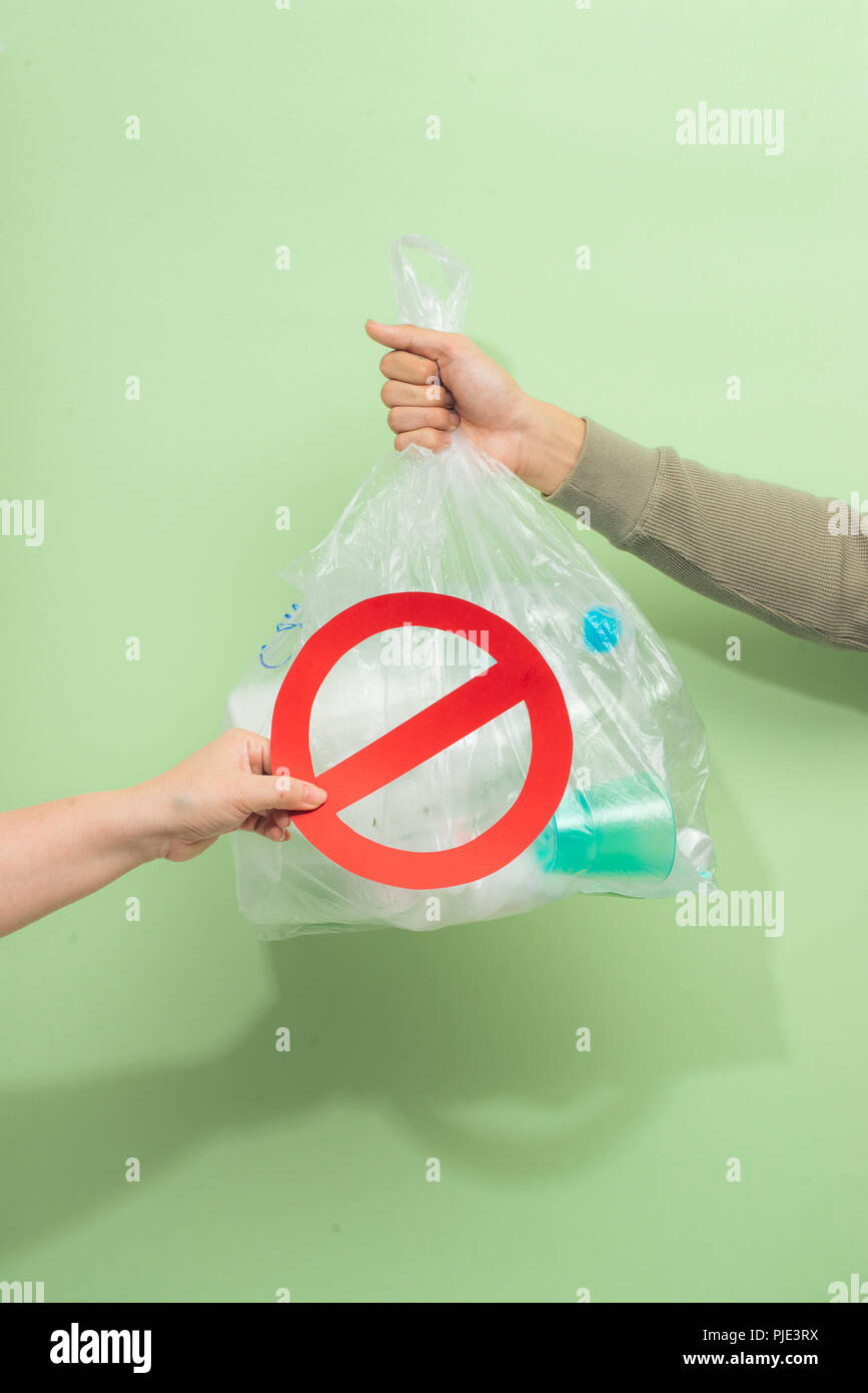 Männliche hand mit einem abfallbeutel auf grünem Hintergrund isoliert. Stockfoto