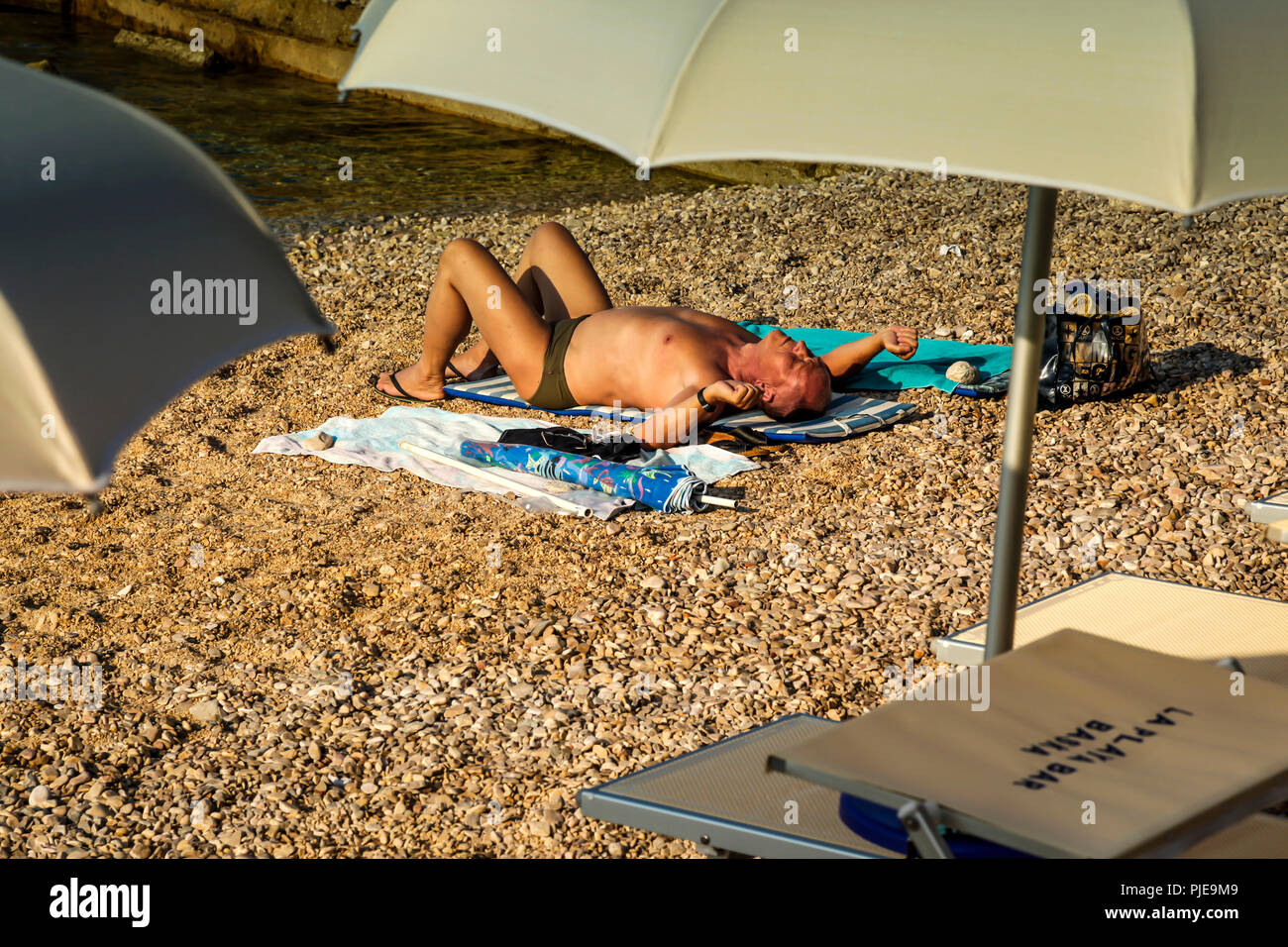 Man liegt am Strand matte Sonnenbaden an der Adriatischen Küste auf der kroatischen Insel Krk im Resort von Baska Stockfoto