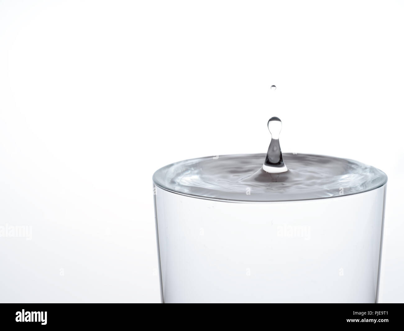 Tropfen Wasser, über das Glas Überlauf zu machen und über. Auf weiß. Stockfoto