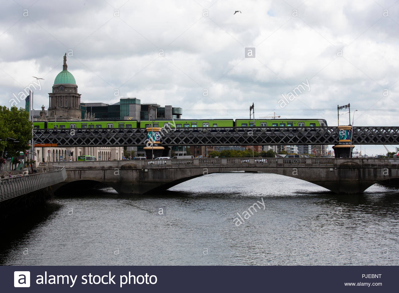 Eine grüne DART Zug überquert den Fluss Liffey in Dublin an einem hellen Sommer. Stockfoto