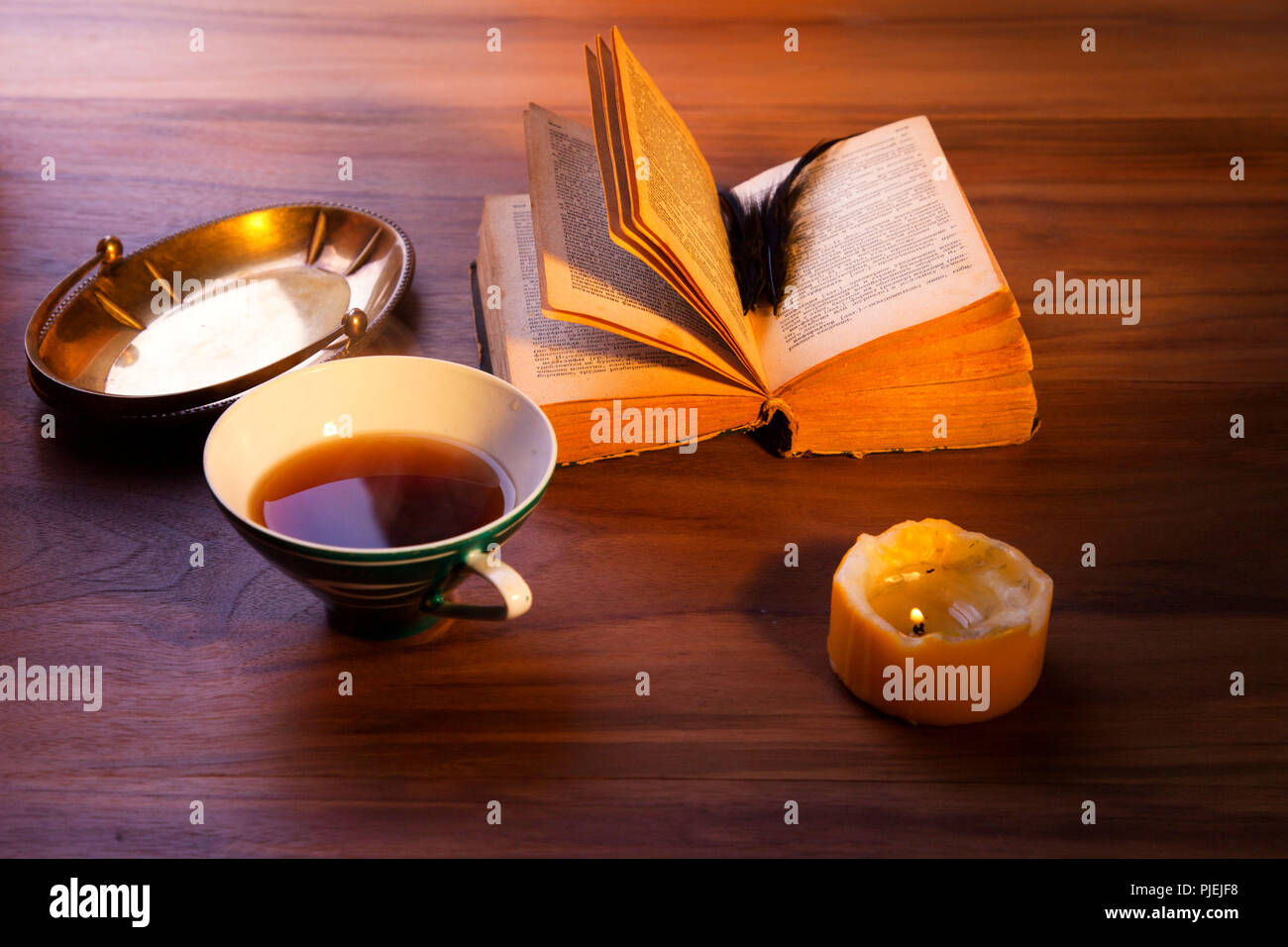 Ein offenes Buch auf dem Tisch. Ein düsteres brennende Kerze. Stockfoto