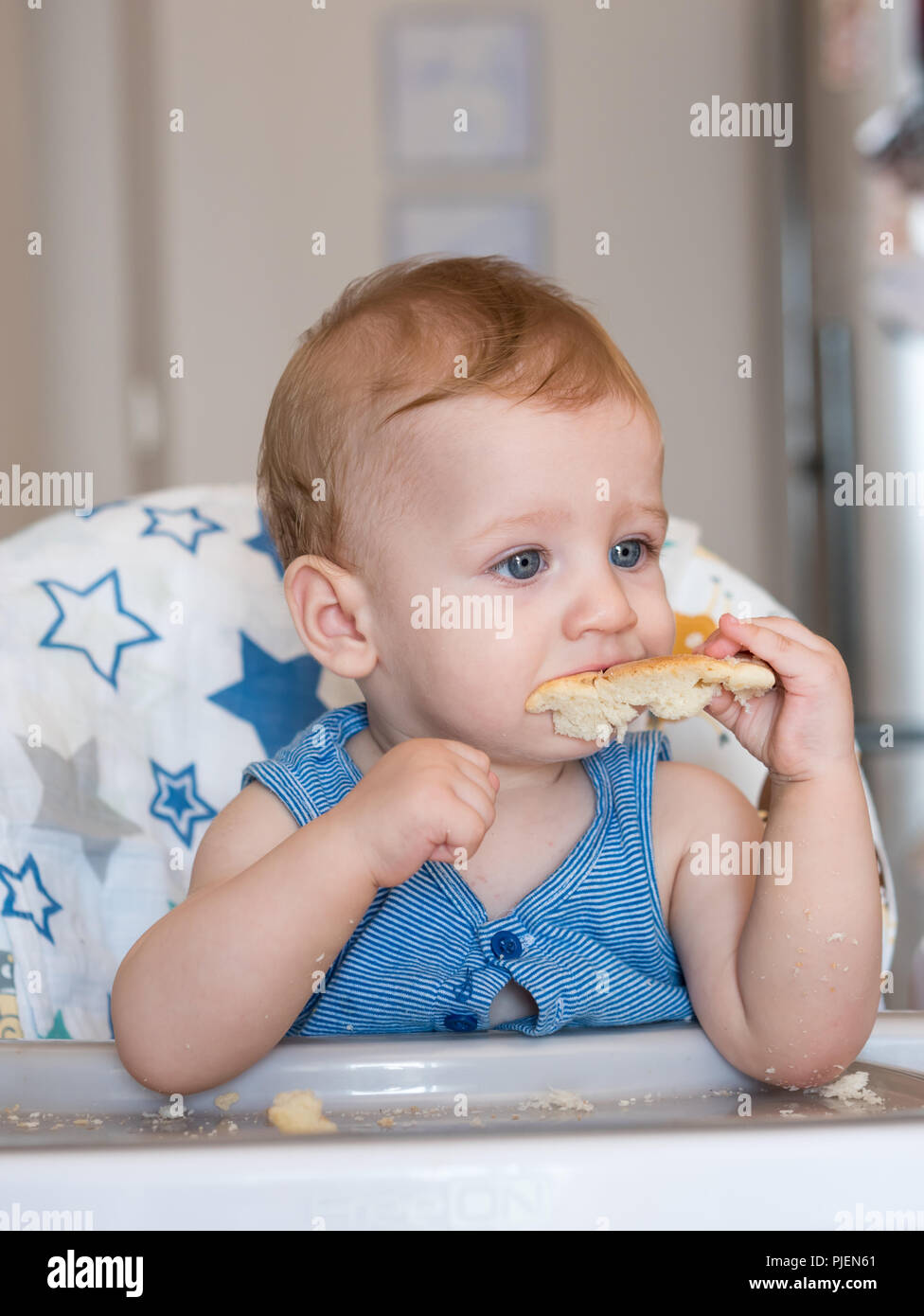 Kleines Baby Junge mit blauen Augen essen Brot Stockfoto