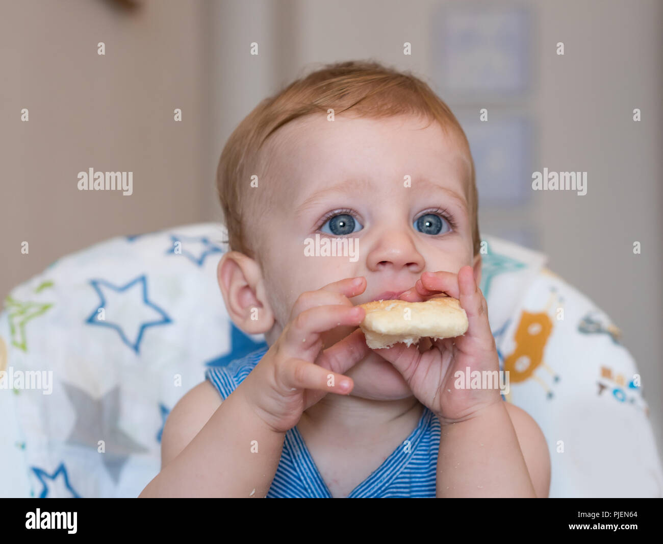 Kleiner Junge mit blauen Augen essen Brot zu Hause Nahaufnahme Stockfoto