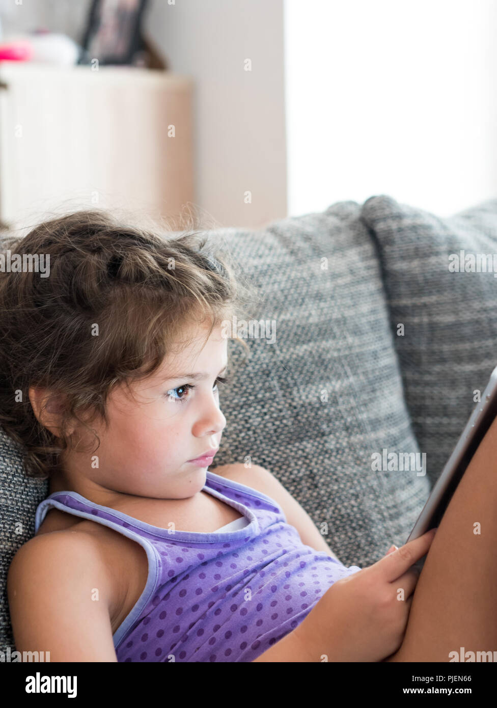 Kleines Mädchen sitzt auf einem Sofa und beobachten Film auf Tablet Computer zu Hause. Stockfoto