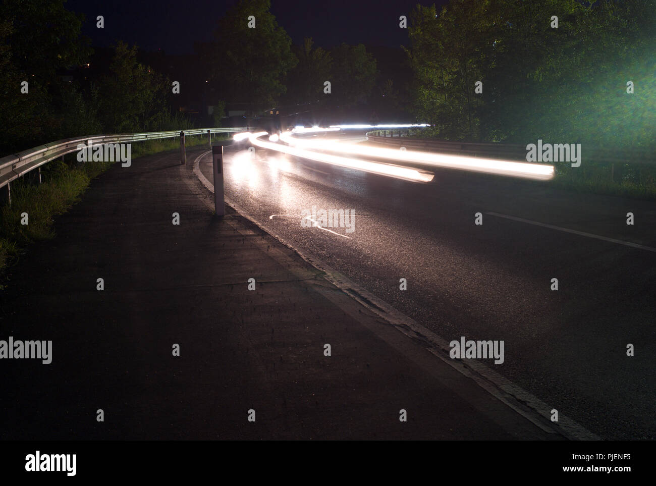 Verkehr in der Nacht Licht Wanderwege auf einer Landstraße Ecke - Lange Belichtung Stockfoto