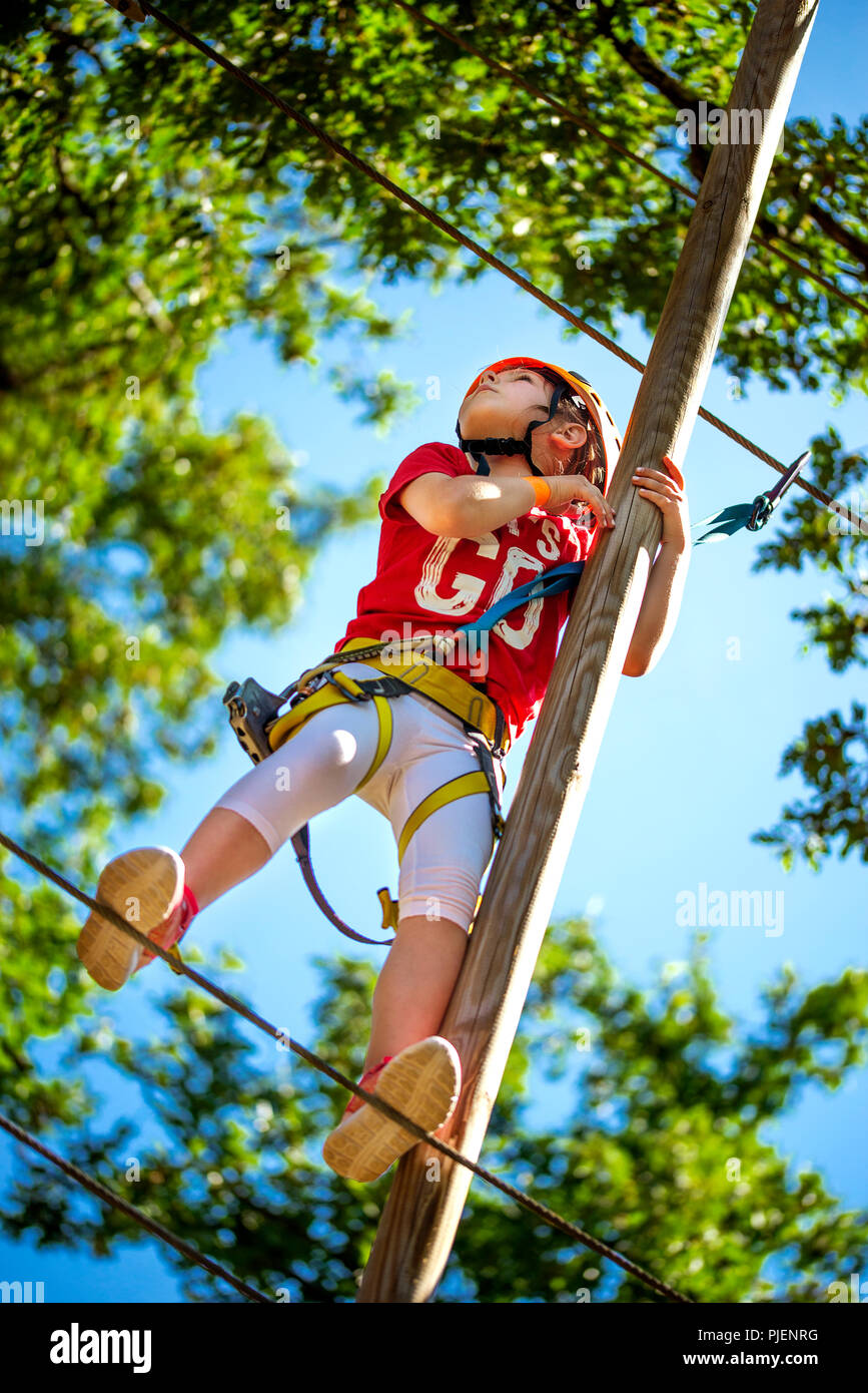 Wenig kaukasische Mädchen an outdoor Baumwipfel klettern Adventure Park brave Stockfoto