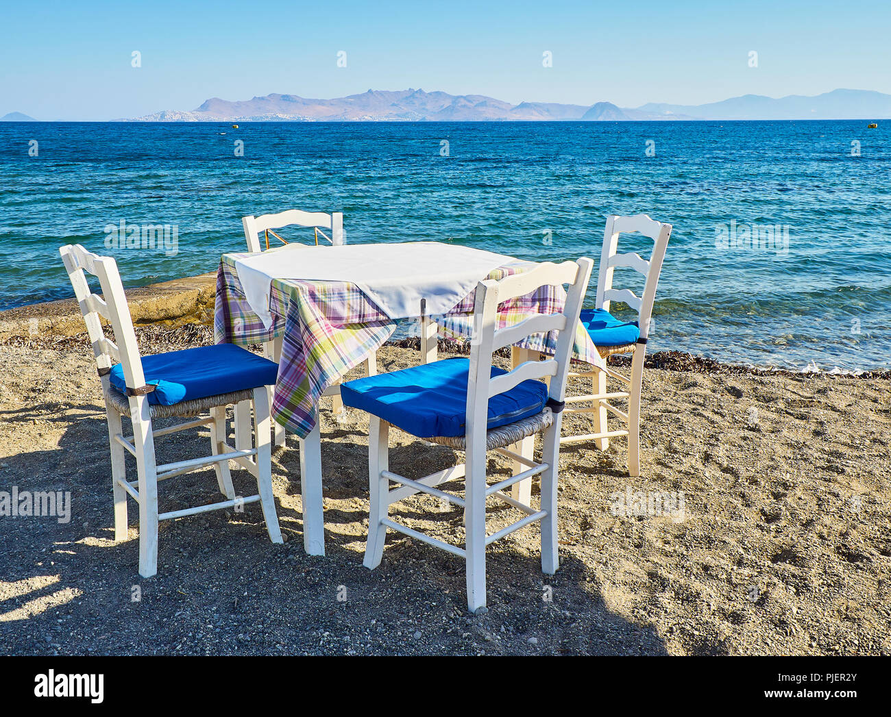 Ein Tisch mit Stühlen, eine griechische Taverne in der Nähe des Meeres in einem Strand der Insel Kos, Griechenland. Stockfoto