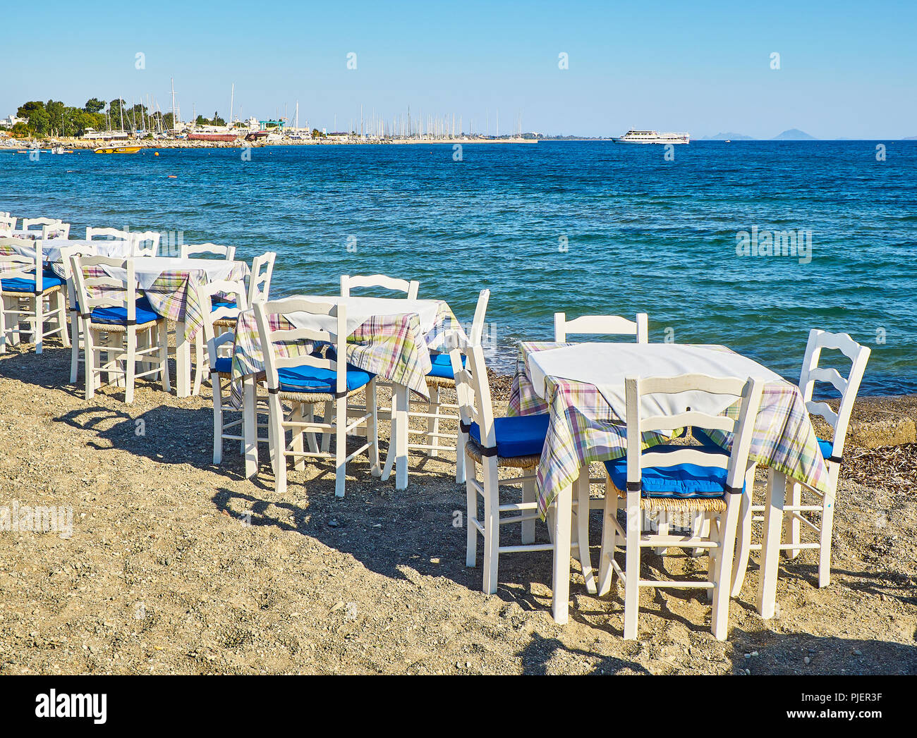 Tische und Stühle für eine griechische Taverne in der Nähe des Meeres in einem Strand der Insel Kos, Griechenland. Stockfoto