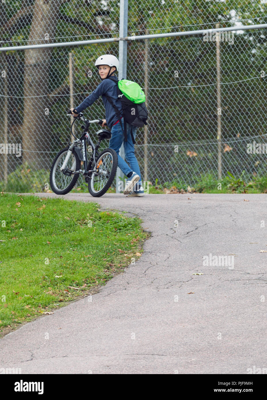Jungen Schwedischen 10-jährige Junge trägt einen Fahrradhelm, Fahrrad auf dem Weg zur Schule ein Blick zurück über die Schulter an Kamera Stockfoto