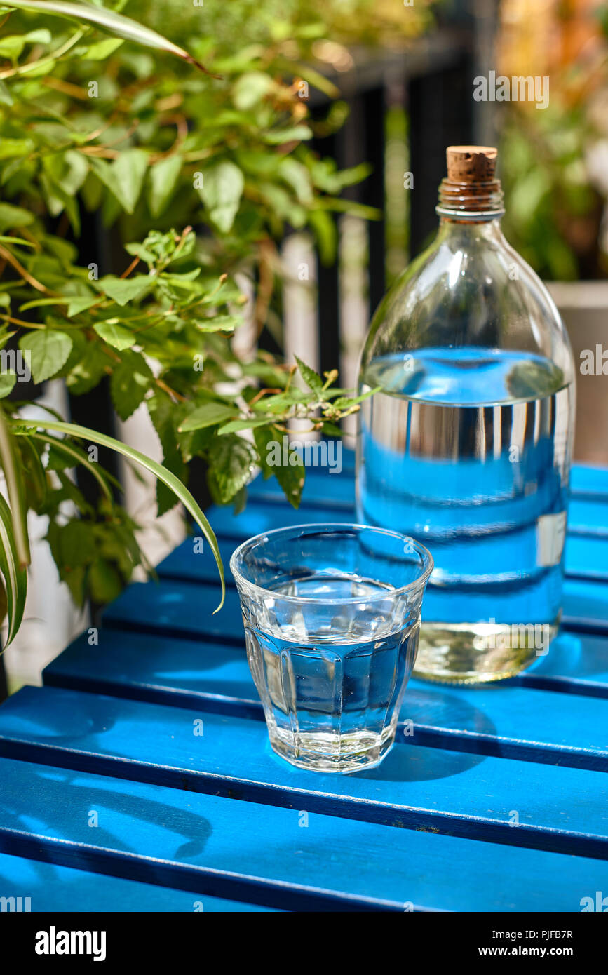 Das glas Flasche Leitungswasser auf dem blauen Tisch im sonnigen Tag Stockfoto