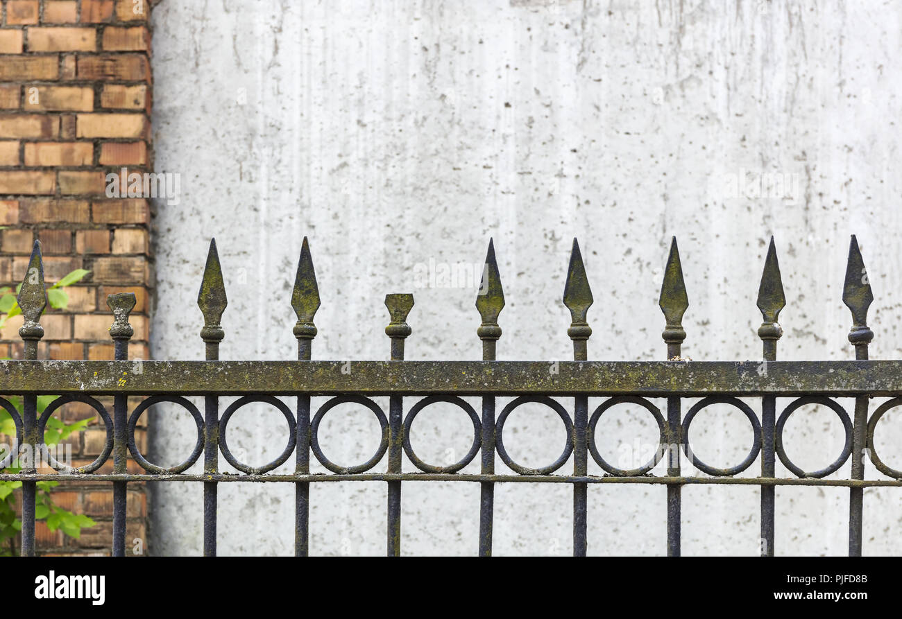 Altmodische rusty spike Zaun gegen verwackelte Betonwand Stockfoto