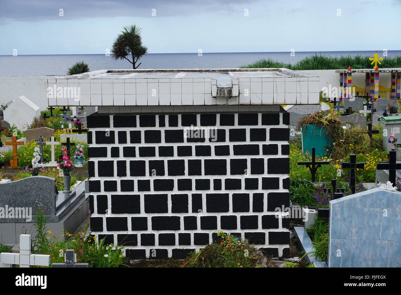 Schöne schwarze und weiße Grabstein auf einem bunten Friedhof mit Meerblick auf La Réunion, Frankreich an einem heißen Sommertag Stockfoto
