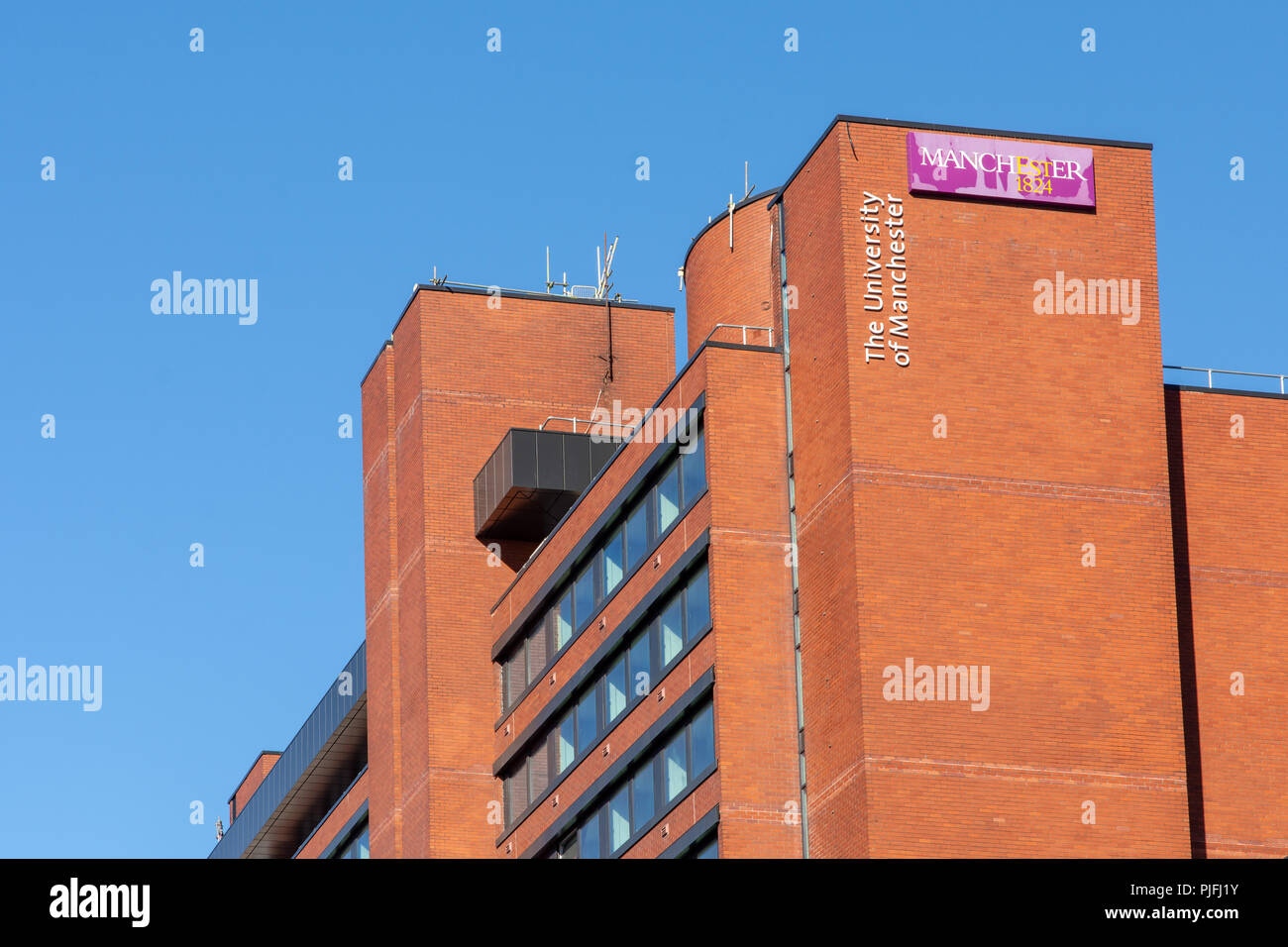 Manchester, England, UK - 30. Juni 2018: Das Logo der Universität Manchester leuchtet durch die Abendsonne auf einem Campus, Gebäude. Stockfoto