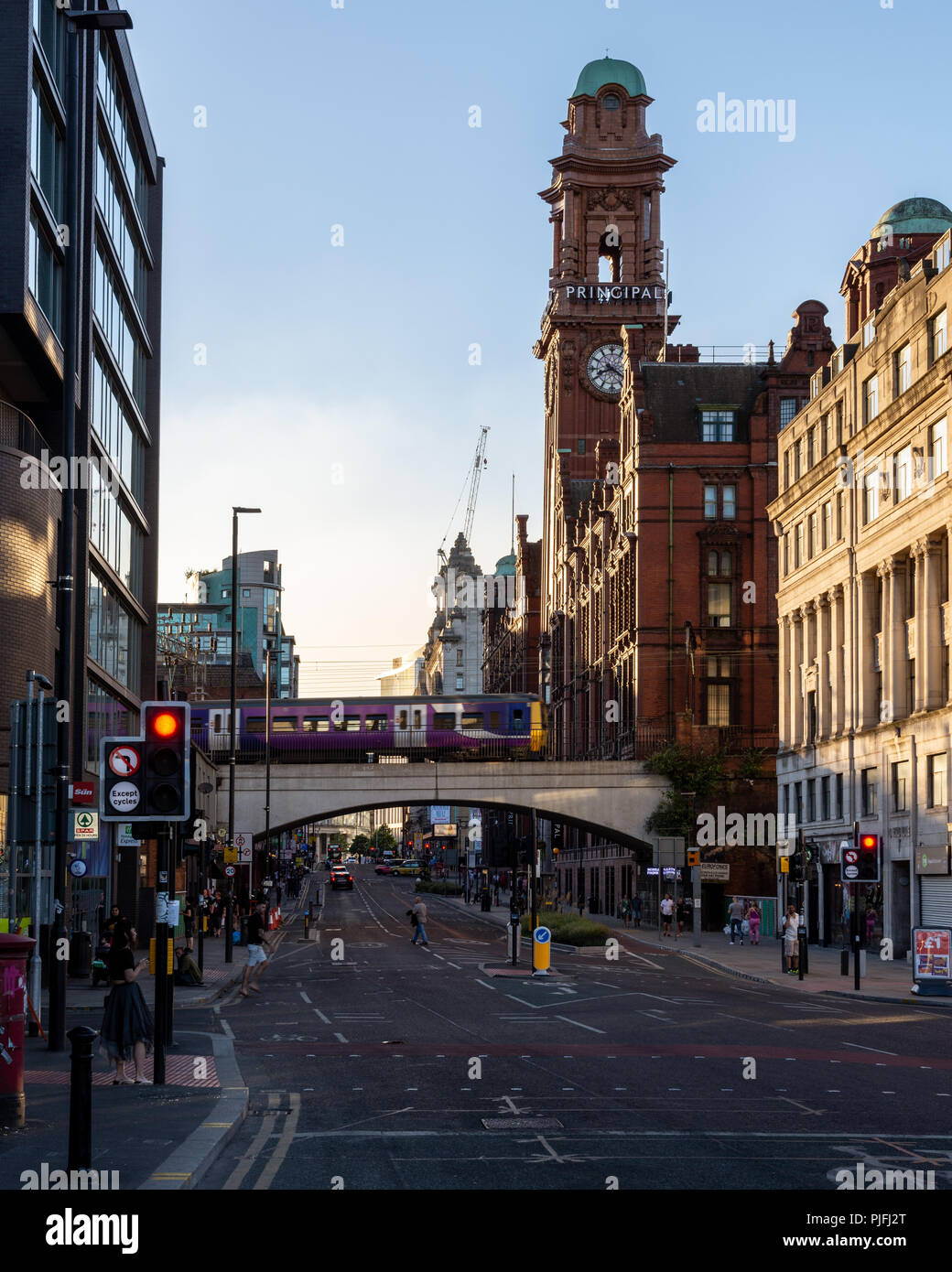 Manchester, England, UK - 30. Juni 2018: Eine nördliche Bahn Klasse 323 elektrische S-Bahn überquert von Manchester Oxford Road, mit dem Glockenturm von t Stockfoto