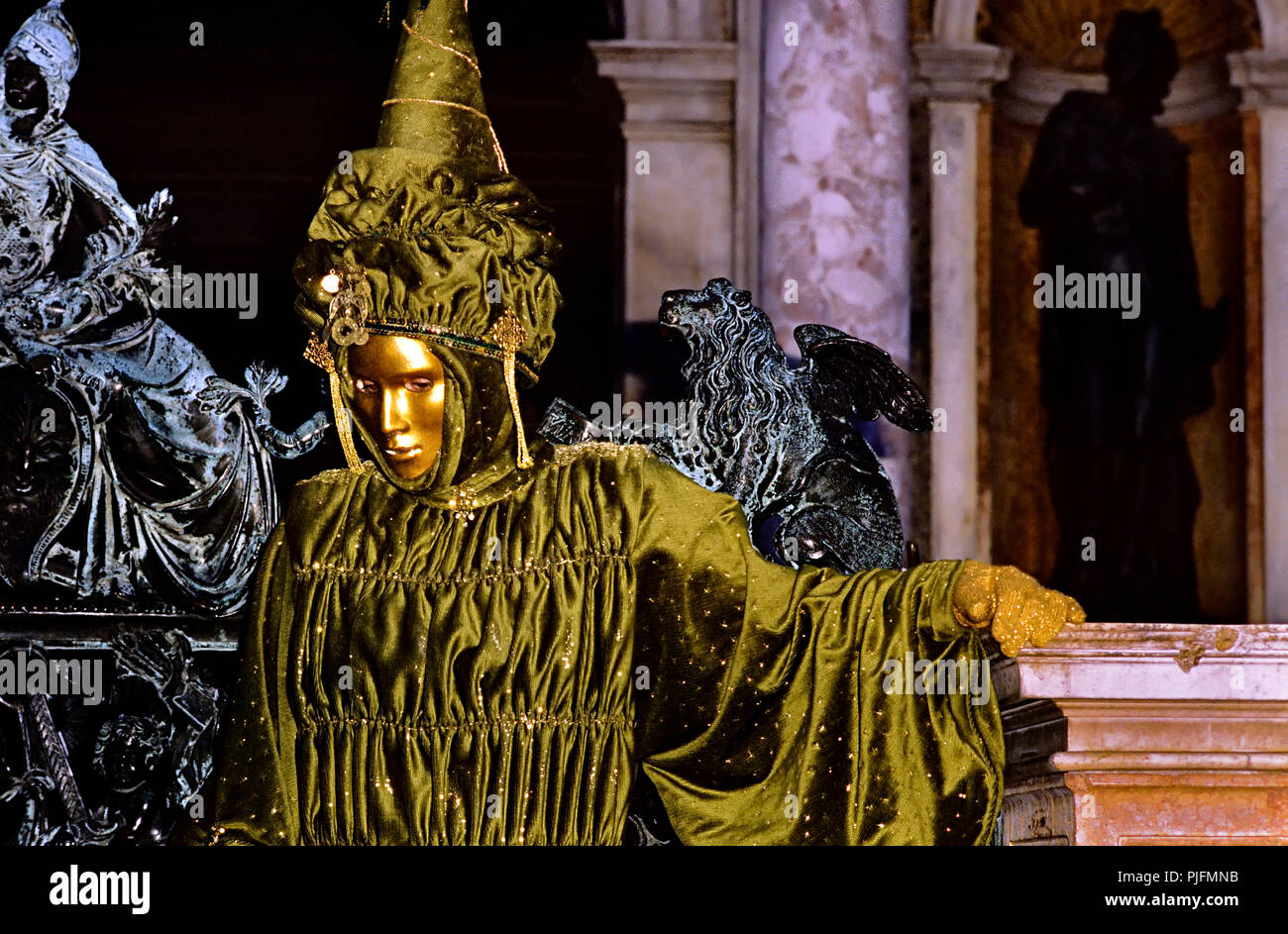 Europa, Italien, Venedig Karneval. Grün und glänzend, gold Maske in der Nähe einer bronzenen Löwen Stockfoto