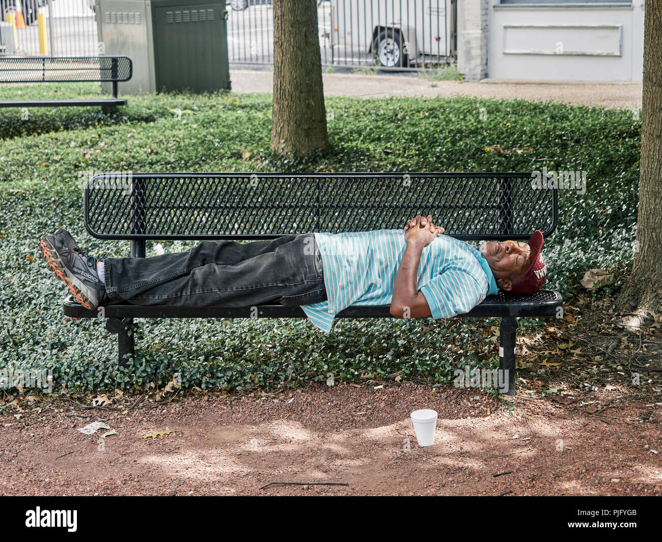 Obdachlosen afroamerikanischen oder schwarzer Mann auf einer Parkbank in Montgomery Alabama, USA schlafen. Stockfoto