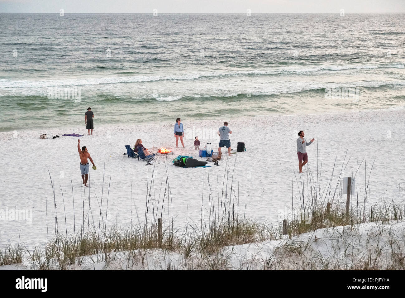 Florida, USA, Strand mit einer Familie oder Menschen spielen um ein Lagerfeuer an der Florida Gulf Coast oder pfannenstiel in der Nähe von Destin am späten Abend oder den Sonnenuntergang. Stockfoto