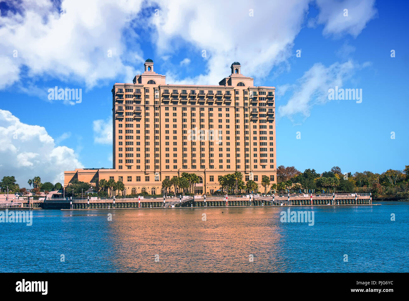 Eine massive braun Hotel Rising in den klaren blauen Himmel auf der Bank eines breiten ruhigen Fluss Stockfoto