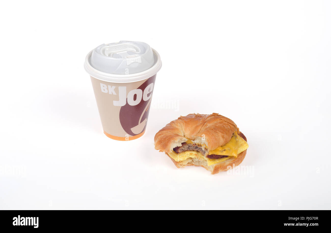Burger King Würstchen, Eier und Käse croissan', oder Croissant Sandwich mit einem Bissen genommen und eine Tasse Kaffee mit der Bezeichnung BK Joe Stockfoto