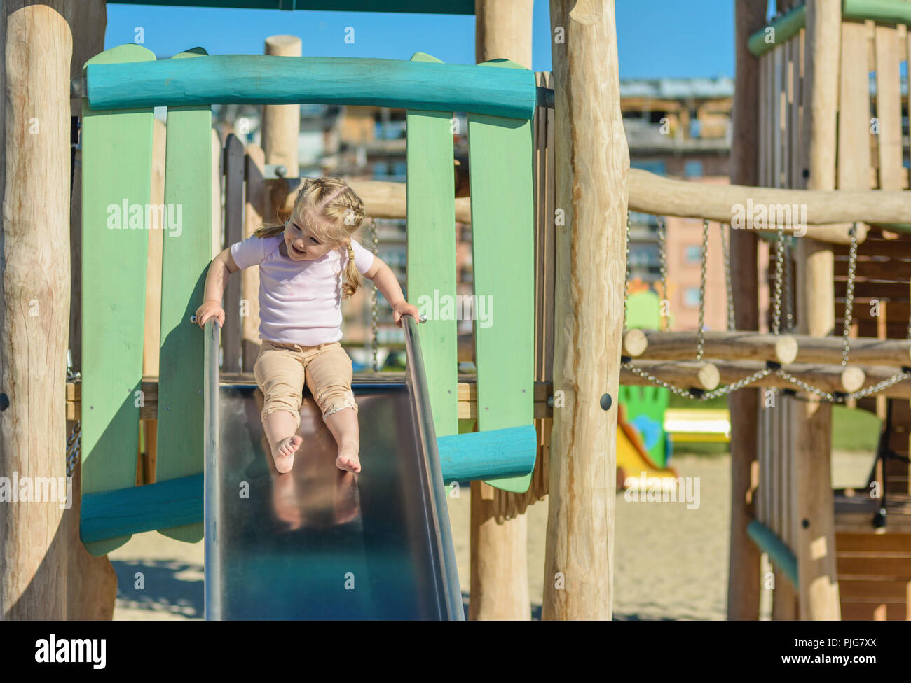 Mädchen von 3 Jahren rutschen Spielplatz im Freien Stockfoto