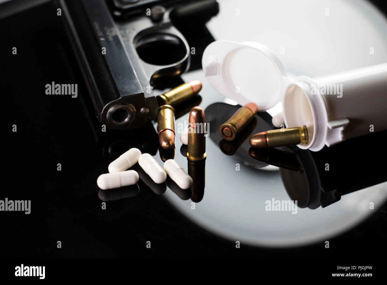 Suizid und psychische Gesundheit Konzept. Schwarze Hand gun Kugeln und Pillen aus einer Flasche auf einem Schwarzen Tisch. Stockfoto