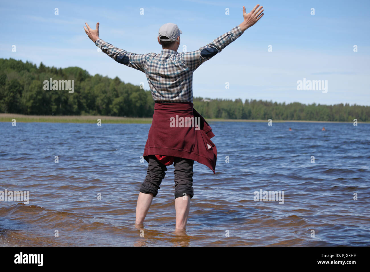 Glücklicher barfuss Mann mit offenen Armen in einem Saimaa See, Finnland Stockfoto