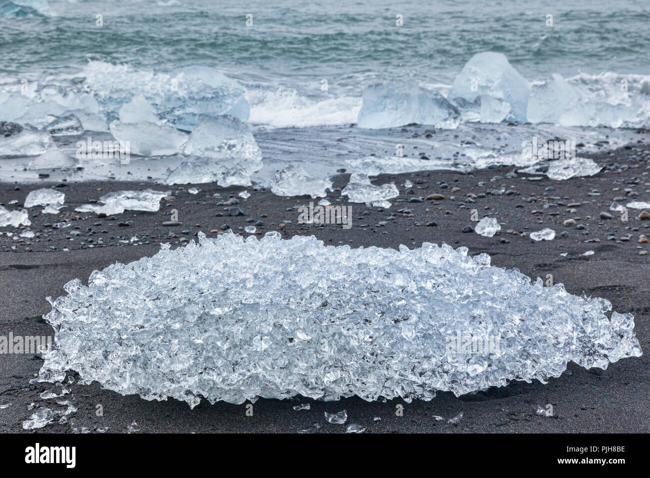 Eis auf Diamond Beach, South Island, wo Eis von Gletschersee Jökulsárlón Gletscherlagune auf der vulkanischen schwarzen Sand abgelagert wird. Stockfoto