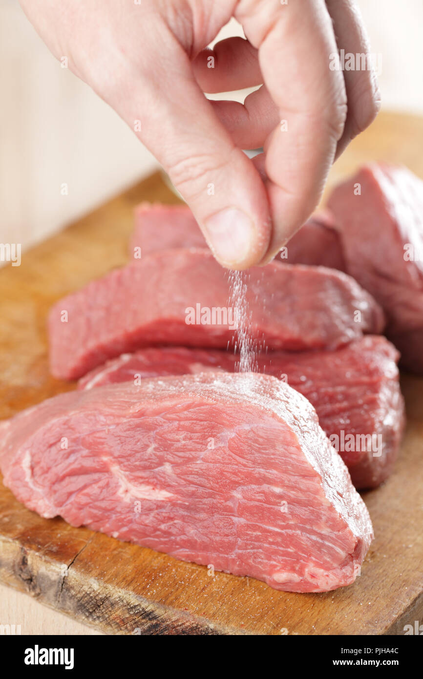 Das Salzen rohes Rindfleisch Steaks auf dem Schneidebrett Stockfoto